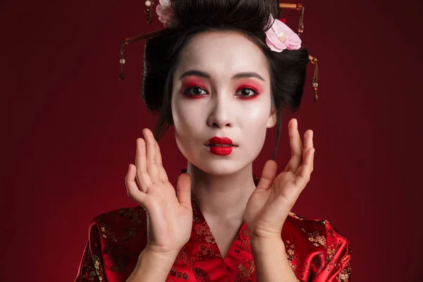 日本传统和服中迷人的亚洲艺妓妇女在红色背景下被隔离的图像 — 图库照片
