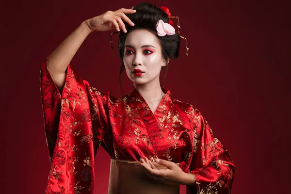 传统日本和服中年轻的亚洲艺妓在红色背景下跳舞的照片 — 图库照片