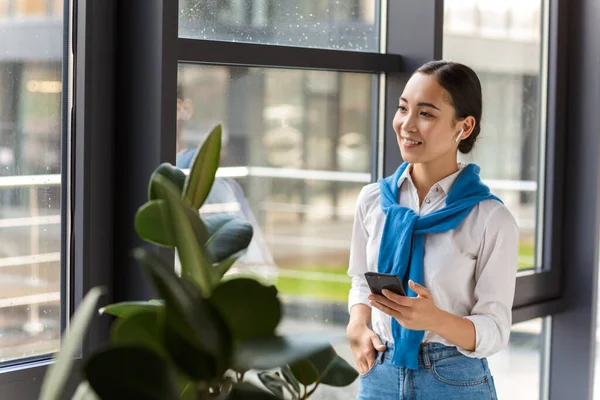 Bild Ung Asiatisk Sekreterare Kvinna Öronsnäckor Som Håller Mobiltelefon Stående — Stockfoto