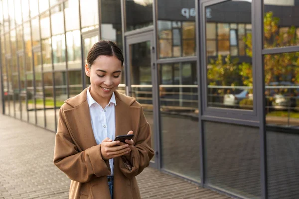 Imagen Joven Morena Mujer Asiática Usando Abrigo Usando Teléfono Móvil —  Fotos de Stock