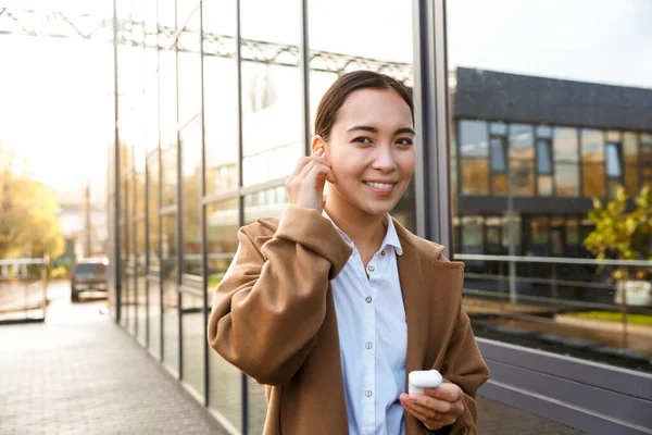 Imagen Joven Morena Mujer Asiática Usando Abrigo Usando Auriculares Mientras —  Fotos de Stock