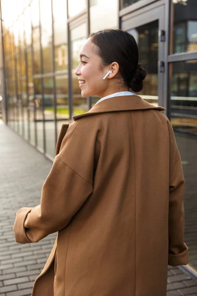 Imagen Joven Morena Mujer Asiática Usando Abrigo Usando Auriculares Mientras —  Fotos de Stock
