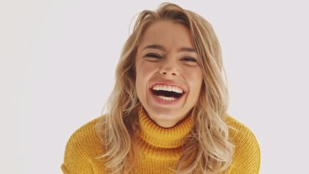笑着漂亮的金发女人穿着毛衣开心地看着相机灰色的背景 — 图库视频影像