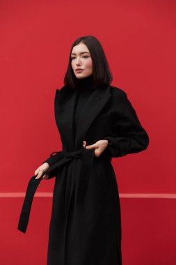 Sonbahar ceketi giyen güzel, genç esmer kadın pembe arka planda tek başına poz veriyor.