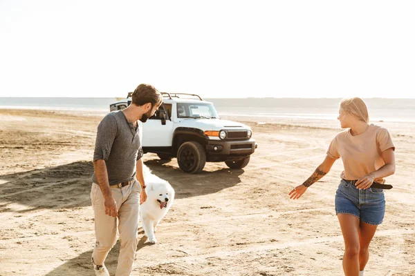 Ελκυστικό Νεαρό Ζευγάρι Παίζει Σκυλί Τους Στην Ηλιόλουστη Παραλία — Φωτογραφία Αρχείου