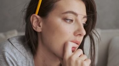 Düşünceli, mutlu, güzel esmer kadının bir şeyler okuyup evdeki kanepede yatarken yüzünü çevirmesi.