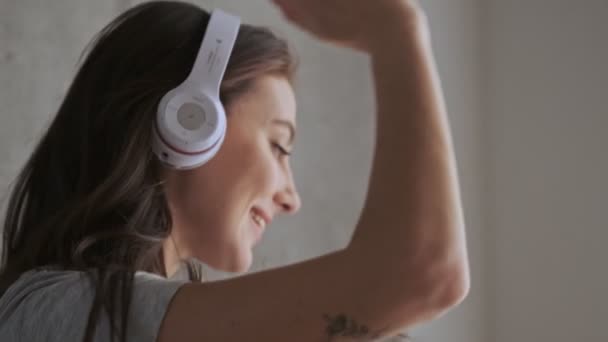Счастливая Симпатичная Брюнетка Наушниках Слушает Музыку Танцует Стены Дома — стоковое видео