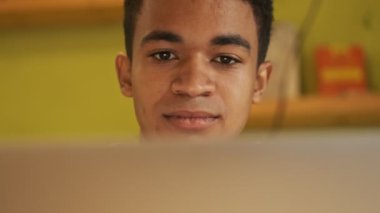 Çekici, ciddi bir Afrikalı çocuk. Ödev yapıyor. Dizüstü bilgisayar kullanıyor..