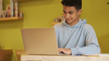 Konsantre olmuş genç Afrikalı öğrenci ödevlerini dizüstü bilgisayarla yapıyor..