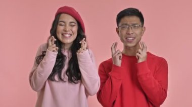 Heyecanlı, gergin, sevimli, sevgi dolu çift pembe duvarın arkasında yalnız. Umut dolu parmaklar yap..