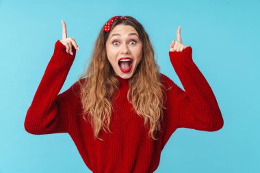 Mavi duvar arkasında izole bir şekilde poz veren gülümseyen, şaşırmış genç bir kadının görüntüsü.