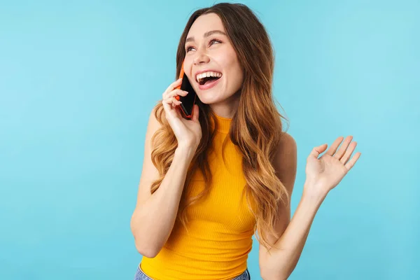 在演播室里一个美丽快乐的高加索女人笑着用蓝色背景的手机聊天的画像 — 图库照片