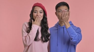 Genç, gülümseyen bir çift pembe duvar arkasında yalnız öpüşüyorlar..