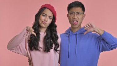 Hoşnutsuz, sevgi dolu genç bir çift pembe duvar arkaplanından izole edilmiş..