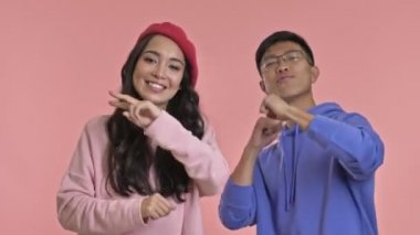 Genç, mutlu, sevgi dolu çift pembe duvar arkasında dans ediyor..