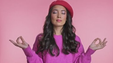 Pembe duvar arkasında yalnız poz veren genç Asyalı kadın meditasyon yapıyor..