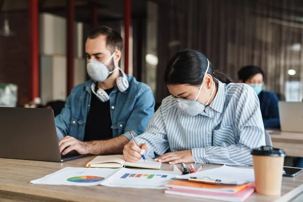 Foto Estudantes Multinacionais Focados Máscaras Médicas Estudando Com Laptop Sala — Fotografia de Stock