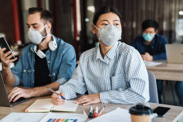 Foto Estudantes Multinacionais Focados Máscaras Médicas Estudando Com Laptop Celular — Fotografia de Stock