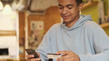 Konsantre pozitif memnun Afrikalı adam cep telefonu kartı kullanıyor..