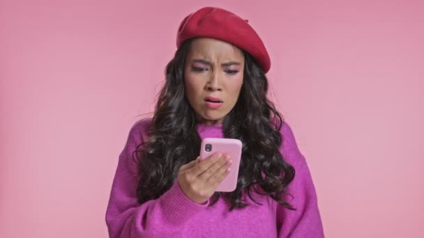 若いです負の不満感情的なアジアの女性Posing絶縁上ピンク壁の背景に使用して携帯電話 — ストック動画