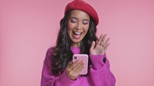 낙관적 이시아인 분홍색 배경으로 고립되어 핸드폰으로 이야기하는 — 비디오