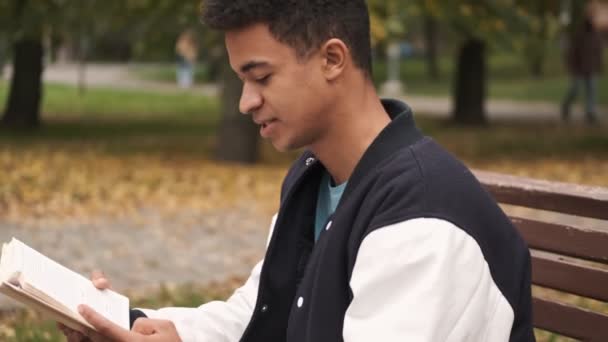 Concentrado Jovem Africano Estudante Sentar Banco Leitura Livro Livre — Vídeo de Stock