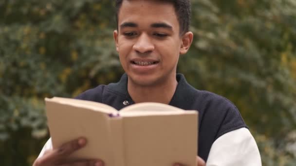 Concentrado Jovem Africano Estudante Sentar Banco Leitura Livro Livre — Vídeo de Stock