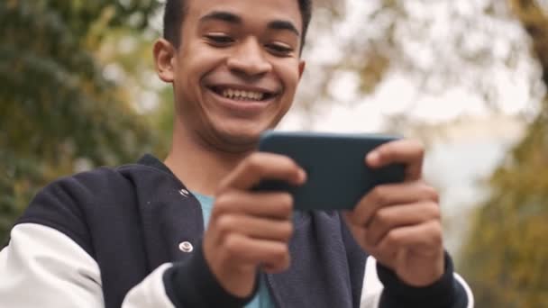 Concentrado Joven Positivo Emocional Africano Chico Estudiante Sentarse Banco Jugar — Vídeo de stock