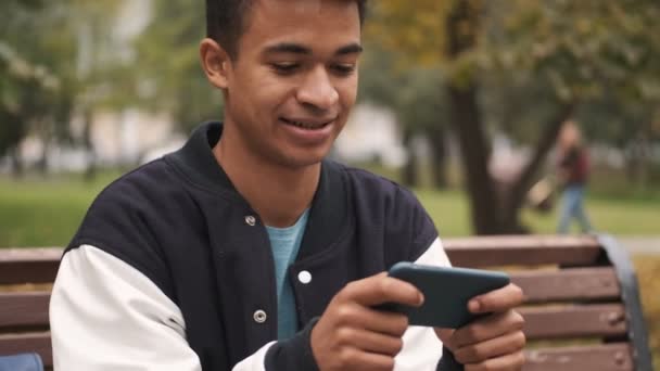 Joven Chico Africano Emocional Estudiante Sentarse Banco Jugar Juegos Por — Vídeo de stock