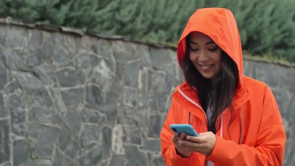 Pretty Asian Cheery Positive Woman Walking Outdoors Orange Coat Using — Stock Video