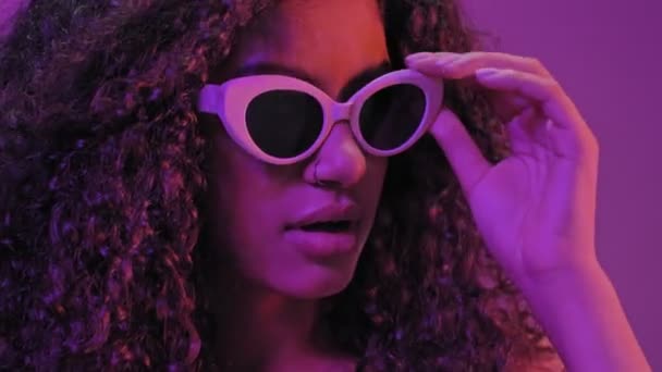 Verwirrte Junge Afrikanerin Mit Sonnenbrille Über Neonviolettem Licht — Stockvideo