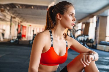 Spor salonunda spor yaparken akıllı yamağı kullanan güzel bir sporcunun portresi.