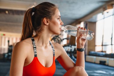 Spor salonunda spor yaparken, akıllı bir şekilde su içen güzel bir sporcunun portresi.