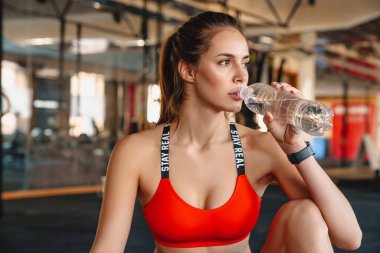 Spor salonunda spor yaparken, akıllı bir şekilde su içen güzel bir sporcunun portresi.