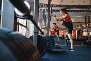 Kendine güvenen genç sporcu kadın spor salonunda esneme egzersizleri yapıyor.