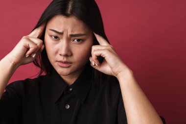 Kırmızı duvar arkasında yalnız poz veren güzel üzgün Asyalı genç bir kadın..