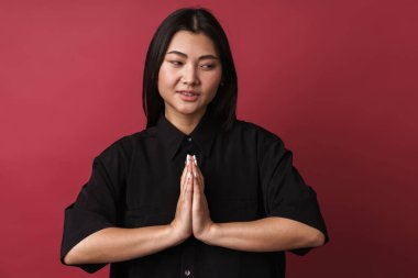 Asyalı iyimser bir genç kadının kırmızı duvar arkasında yalnız poz verirken çekilmiş fotoğrafı meditasyon yap..