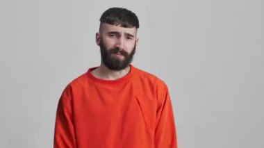 Genç, yakışıklı, ciddi, olumsuz sakallı esmer adam. Gri duvar arkasında izole edilmiş. Hayır diyor..