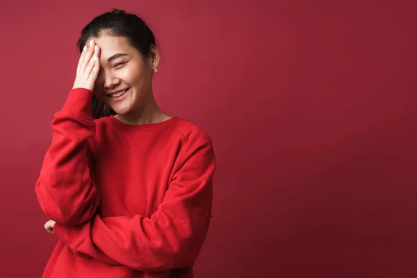 照片中 一个亚洲人微笑着害羞的年轻女子在红墙的背景上孤立无援 — 图库照片