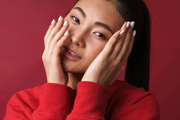 一个漂亮的笑着的年轻亚洲女人穿着休闲装站在红色的背景下 — 图库照片