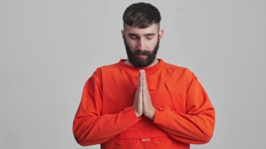 Yakışıklı, gevşetici, ciddi esmer adam. Gri duvarda izole edilmiş. Arka planda meditasyon yapıyor..