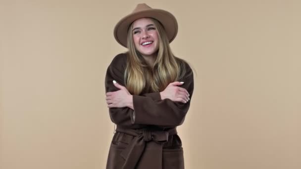 Μια Νεαρή Χαμογελαστή Γυναίκα Που Φοράει Καπέλο Και Παλτό Αγκαλιάζεται — Αρχείο Βίντεο