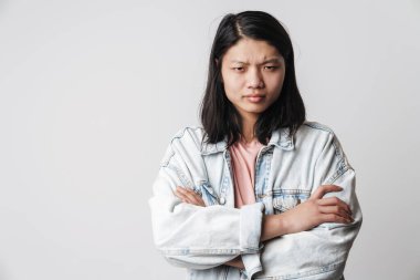 Kamerada elleri çaprazlanmış, beyaz arka planda poz veren hoşnutsuz Asyalı bir adamın görüntüsü