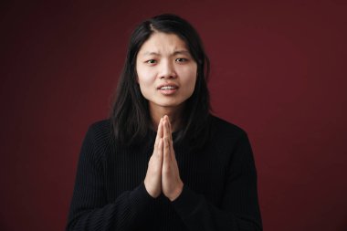 Mutsuz Asyalı bir adamın görüntüsü, avuçlarıyla kamerada poz veriyor. Burgonya arka planında izole edilmiş.