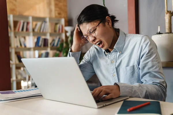 Beeld Van Ontevreden Knappe Aziatische Man Bril Studeren Met Laptop — Stockfoto