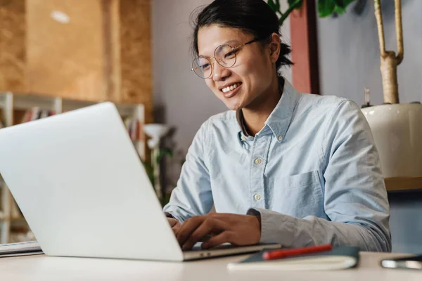 Image Pleased Handsome Asian Man Eyeglasses Smiling Studying Laptop While — Stock Photo, Image