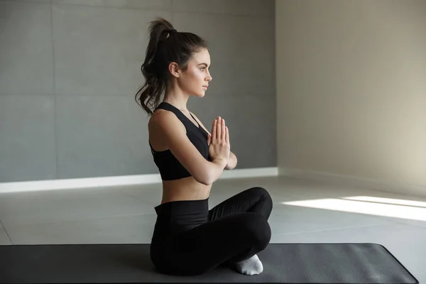 マットの上に座っている間 スポーツウェアの瞑想と一緒に手のひらを保持に焦点を当てた若い女性の写真 — ストック写真