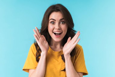 Şok olmuş genç bir kadının mavi duvar arkasında yalnız poz verişi..