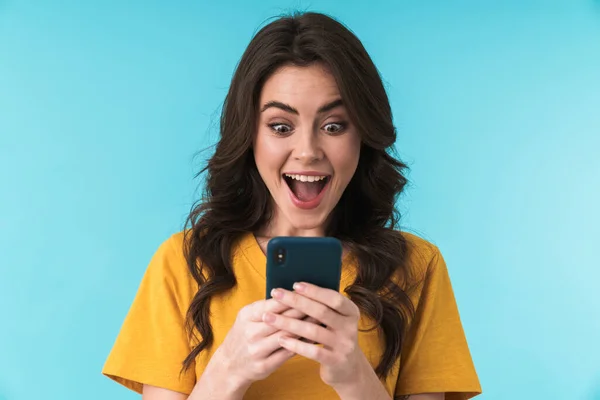 stock image Image of a happy surprised shocked young pretty woman posing isolated over blue wall background using mobile phone.