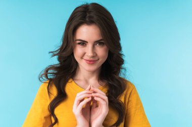 Mavi duvar arkasında izole edilmiş sevimli, iyimser, kurnaz bir kadının fotoğrafı..